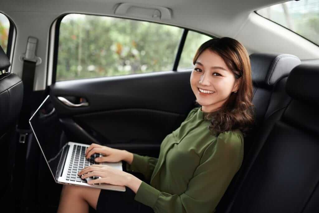 Beautiful young business woman is using laptop in the car to work